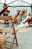 Herbstliche Dekoration mit Trockenblumen in Gewächshaus, Brautpaar im Hintergrund