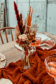 Autumnal bouquet of flowers in a glass vase on a rustic dining table