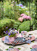 Gartentisch mit Teeservice und Blumenarrangement