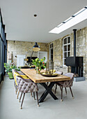 Dining area with long wooden table, upholstered chairs and unplastered walls