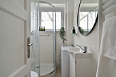 Brightly tiled bathroom with shower cubicle and round mirror