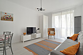 Hell eingerichtetes Wohnzimmer mit grauen und orangefarbenen Akzenten
