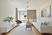 Hell eingerichtetes Wohnzimmer mit weißem Sofa und modernen Leuchten