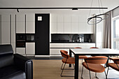 Moderne Küche in Schwarz-Weiß mit Esstisch und farbigen Designerstühlen