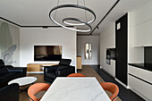 Modernes Wohn- und Esszimmer mit Ring-Pendelleuchte und schwarz-weißer Küchenzeile