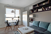 Modern eingerichtetes Wohnzimmer mit Essbereich und geometrischen Regalen