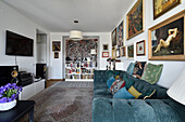 Wohnzimmer mit Kunstwerken, Samtsofa und klassischem Teppich