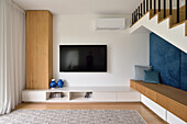 Modernes Wohnzimmer mit TV-Bildschirm und blauen Akzenten an der Wand