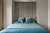 Modernes Schlafzimmer mit Betonwand und blauer Bettwäsche