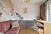 Modernes Arbeitszimmer mit Schreibtisch, rosafarbenem Samt-Sofa und floraler Tapete