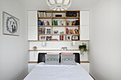 Schlafzimmer mit Bücher-Wandregal und Kissen mit Schriftzug