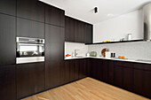 Moderne Küche mit dunkelbraunen Schränken und Holzboden