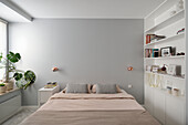 Minimalistisches Schlafzimmer mit Einbau-Regalwand und kupfernen Wandlampen