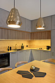 Moderne Küchenzeile mit Holz- und Betonoptik und geometrischen Hängeleuchten