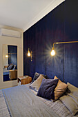 Dunkelblaue Wandvertäfelung und goldene Wandlampen im Schlafzimmer