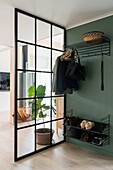 Black wardrobe and sliding glass door in the entrance area with green wall