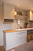 Kitchen unit with wooden worktop and light grey cupboards