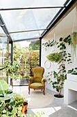 Brightly designed conservatory with plants and green armchair