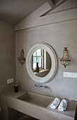 Round mirror with ornaments above modern washbasin in bathroom