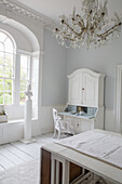 Bright room in shabby chic style with secretary and chandelier