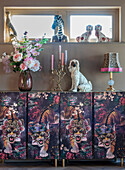 Vase with flowers and candlestick on cupboard with tiger motif