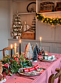 Festive table setting with Christmas decorations, candles and miniature fir trees