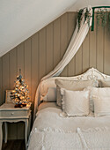 Christmas-decorated bedroom with canopy and small Christmas tree