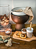 Wooden table with tea light, biscuits, bowls and natural decorations