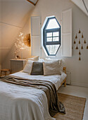 Country-style bedroom with octagonal window, bed and decorations