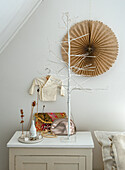 Decorated bedside table with tree of lights and dried flowers, paper rosette on the wall