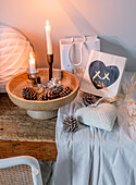 Decorative arrangement of candles, cones and bags on a wooden table