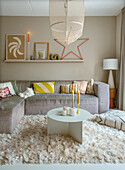 Living room with grey corner sofa, cushions and fluffy rug