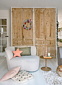 Modern armchair and side table in front of rustic wooden cupboards in the living room