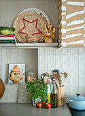 Kitchen corner with herb pot, cooking utensils and wall tiles