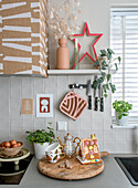 Kitchen corner with wooden board, gingerbread house and herb pots