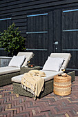 Sun loungers with cushions and blanket on a terrace made of brick slabs