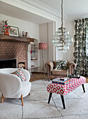 Cosy living room with patterned stool, vintage chandelier and brick fireplace