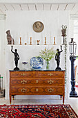 Antique wooden chest of drawers with porcelain crockery and sculptures in the living room