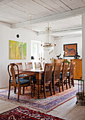 Dining room with wooden ceiling, crystal chandelier and large wooden table on Persian carpet