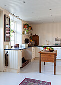 Country-style kitchen with wooden table as island in the center