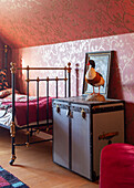 Bedroom with metal bed and antique sailor's trunk as bedside table