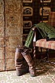 Rustic cloakroom area with checkered armchair, boots and green coat