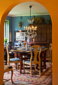 Dining room with chandelier, rustic wooden furniture and colorful patterned carpet