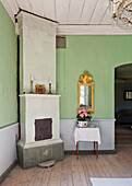 Light green painted room with antique tiled stove and gilded mirror