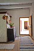 Old-fashioned hallway with wooden furniture and striped runner with a view into a sunny room