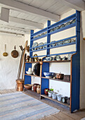 Country-style shelf with blue and white ceramics and copper utensils in a rustic room