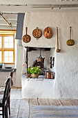 Historic kitchen with copper crockery on rustic wall and open fireplace