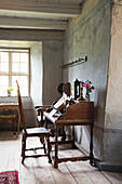 Antique wooden secretary in historic room with wooden floorboards and plaster walls