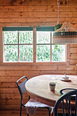 Round wooden table in front of window in wooden house