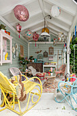 Colourfully decorated garden shed with rattan furniture, lamps and lanterns